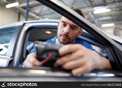 service, repair, maintenance and people concept - mechanic man with automotive diagnostic scanner checking car system at workshop