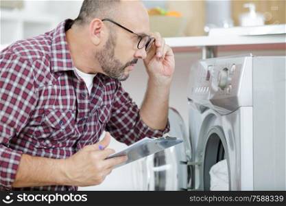 serviceman putting on eyeglasses to look at washing machine