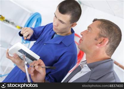 serviceman uses screwdriver to fix an electronic device