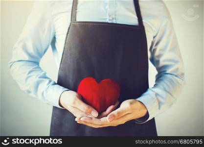 Servicing man in apron holding heart - customer relationship and service minded business concept. Servicing man in apron holding heart - customer relationship and service minded business concept.