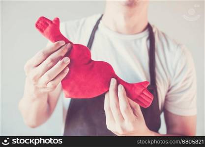 Servicing man in apron holding open armed heart with hands - customer relationship and service minded business concept. Servicing man in apron holding open armed heart with hands - customer relationship and service minded business concept.