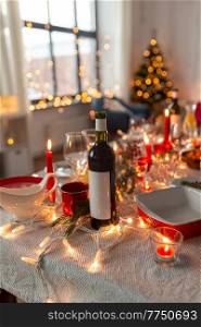 serving, winter holidays and celebration concept - bottle of red wine on table served for christmas dinner party at home. bottle of wine on table served for christmas party
