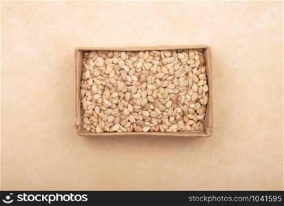 Sesame in small carton on brown background