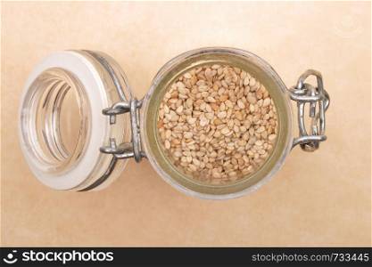Sesame in small glass on brown background