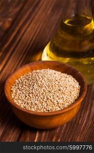 Sesame oil in a glass bottle with a cork and heap sesame seeds in a wooden bowl. The Sesame oil