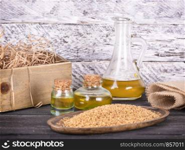 Sesame oil in glass and seeds on lod wooden background