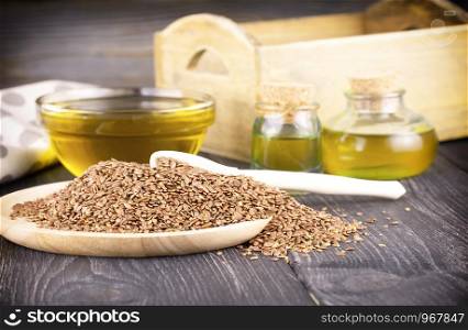 Sesame oil in glass and seeds on wooden background
