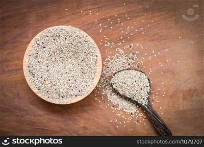 sesame seeds in a wooden bowl and spoon on wood table background , top view