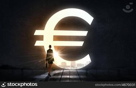 Set big financial goals. Silhouette of businesswoman in light of big euro symbol