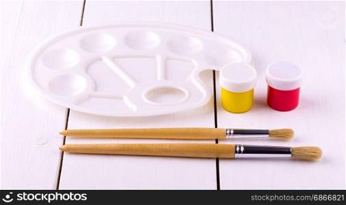Set for drawing brushes, palette on white wooden table