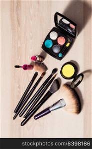 Set for make-up: brushes and cosmetic products on wooden table, close-up. Cosmetics on a wooden background