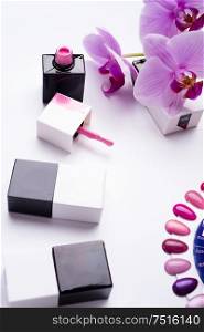 set for manicure with gel polish bottles, color palette and orchid on white background.