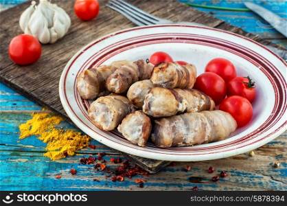 set fried meat sausages on wooden background. Turkey sausages roasted on round plate on wooden surface with tomatoes and spices.The image is tinted.Selective focus