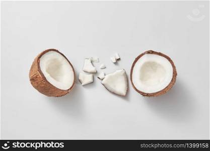 Set from freshly brocken ripe natural organic exotic coconut fruit on a light grey background with soft shadows and copy space. Vegan concept. Top view.. Two halves of fresh natural organic coconut fruit on a light grey background.