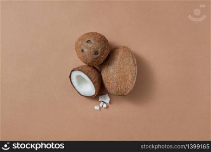 Set from ripe natural organic exotic coconut fruit two whole and one half on a brown background with soft shadows and copy space. Vegan concept. Top view.. Three fresh natural organic coconut fruits on a brown background.