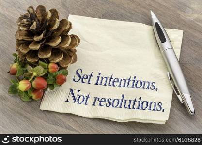 Set intentions. Not resolutions. New Year goals concept. Handwriting on a napkin with a pine cone.