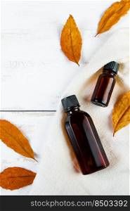 Set of bottles with essence oil or cosmetic serum on a white background. Autumn skin care concept. Eco-friendly cosmetics and yellow fallen leaves. Copy space.. Set of bottles with essence oil or cosmetic serum on a white background. Autumn skin care concept. Eco-friendly cosmetics and yellow fallen leaves.