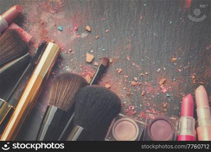 set of brushes, lipsticks and eye shadows with copy space on black background, retro toned. brushes on eye shadows palette