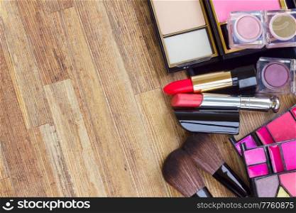 set of brushes, lipsticks, eye shadows with copy space on wooden table desktop. set of make up