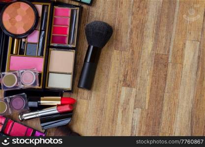 set of brushes, lipsticks, maskara, eye shadows with brush, copy space on wooden table bakcground. set of make up
