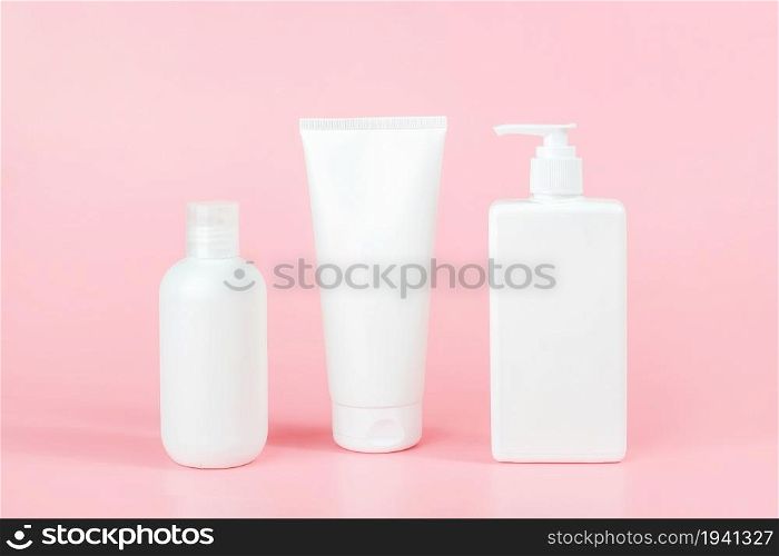 Set of care cosmetic for skin, body or hair. Three white blank cosmetics bottles, tube on pink background. Spa Cosmetic Beauty Concept. Front view Mockup.. Set of care cosmetic for skin, body or hair. Three white blank cosmetics bottles, tube on pink background. Spa Cosmetic Beauty Concept. Front view Mockup