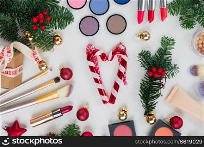 Set of Christmas make up cosmetics products with evergreen tree flat lay styled scene. Christmas make up cosmetics