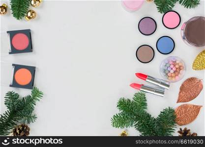 Set of Christmas make up cosmetics products with evergreen tree twigs and copy space. Christmas make up cosmetics