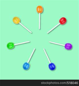 Set of colorful lollipops grouped in a circle isolated on green background. Candy on a stick. Food background. Flat lay.. Set of colorful lollipops grouped in a circle isolated on green background.