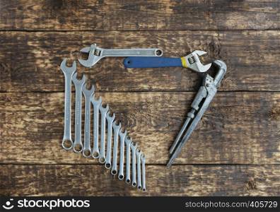 Set of combination wrenches and old adjustable wrenches on an old wooden boards background. Set of combination wrenches and old adjustable wrenches on an old wooden background