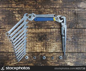 Set of combination wrenches and old adjustable wrenches on an old wooden boards background. Set of combination wrenches and old adjustable wrenches on an old wooden background