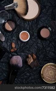 set of cosmetics and nature chocolate on black background 