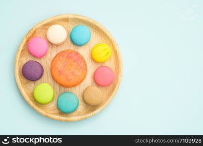 Set of different colorful macaroons Placed in a wooden tray on blue background, Sweet and tasty for cooking and restaurant menu, Dessert beautiful, Top view, Space to write at right.