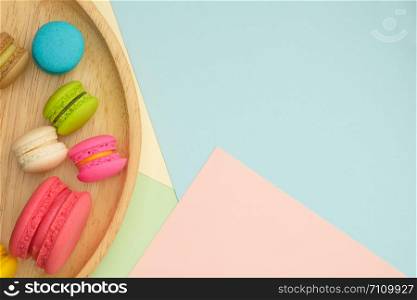 Set of different colorful macaroons Placed in a wooden tray, on many colors background. Sweet and tasty for cooking and restaurant menu. Top view, Space to write at right.