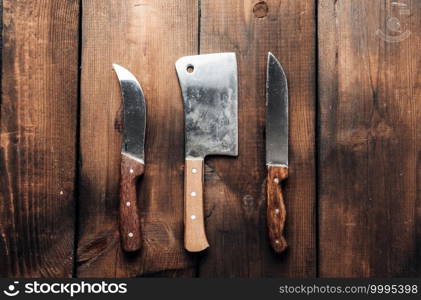 set of different kitchen knives with wooden handles on a brown background from boards, top view