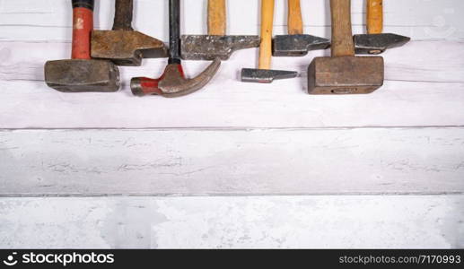 set of different types of old hammers in line at the top of a space on a wooden background. top view with space for text.. set of different types of old hammers in line at the top of a space on a wooden background. top view with space for text