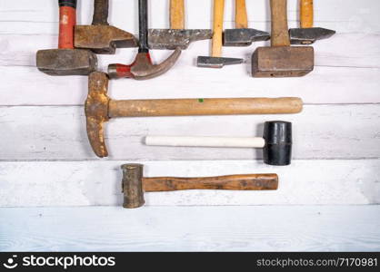 set of different types of old hammers on a wooden background. top view.