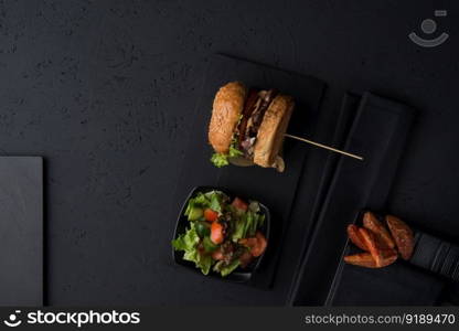 set of fast food, cheeseburger with salad and potatoes on a black background, top view. fast food on a black background