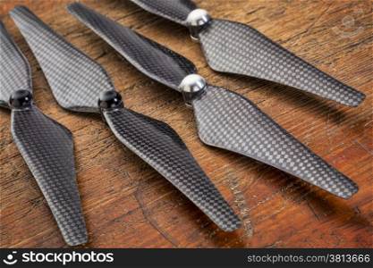 set of four carbon fiber self-tightening propellers for a quadcopter drone against grunge wood