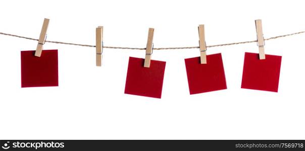 Set of four red blank paper notes held on a string with clothespins isolated on white background. Set of blank notes held on string isolated
