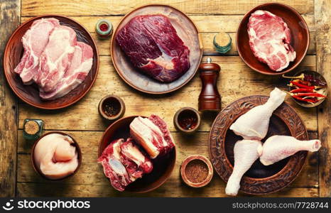 Set of fresh meat on rustic wooden table.Beef,pork and chicken meat on the kitchen table.Top view. Various uncooked meat