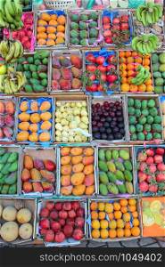Set of fruit is sold in tray from street vendor. Fruit trays for sale of mangoes, pomegranates, bananas, plums, guava, oranges. Fresh fruits in shop. Fruit market with various colorful fresh fruits. Fruit trays for sale of mangoes, pomegranates, bananas, plums, guava, oranges