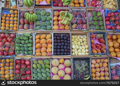 Set of fruit is sold in tray from street vendor. Fruit trays for sale of mangoes, pomegranates, bananas, plums, guava, oranges. Fresh fruits in shop. Fruit market with various colorful fresh fruits. Fruit trays for sale of mangoes, pomegranates, bananas, plums, guava, oranges