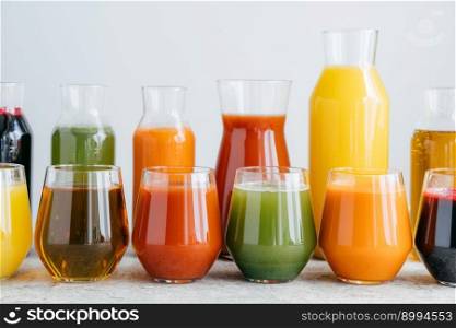 Set of glass jars with multicolored drinks standing in row. Fresh juice made of different fruit isolated over white background. Summer drink