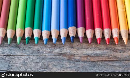 Set of multi-colored pencils on a rustically wooden table, copy space