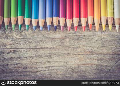 Set of multi-colored pencils on a rustically wooden table, copy space