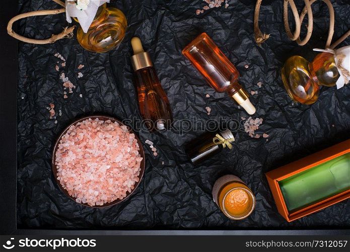 set of nature precious oils and  cosmetics on black background in black frame.
