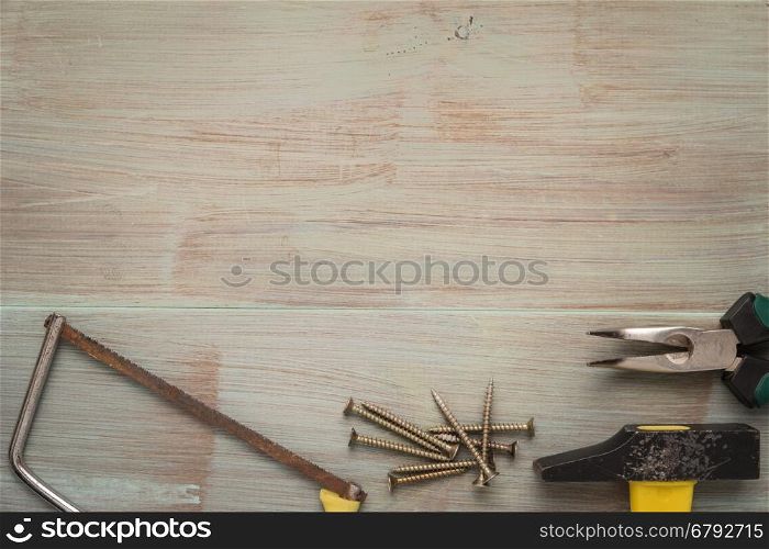 Set of saw, plier, screw and hammer. Tools over a wood panel. Top view with copy space.