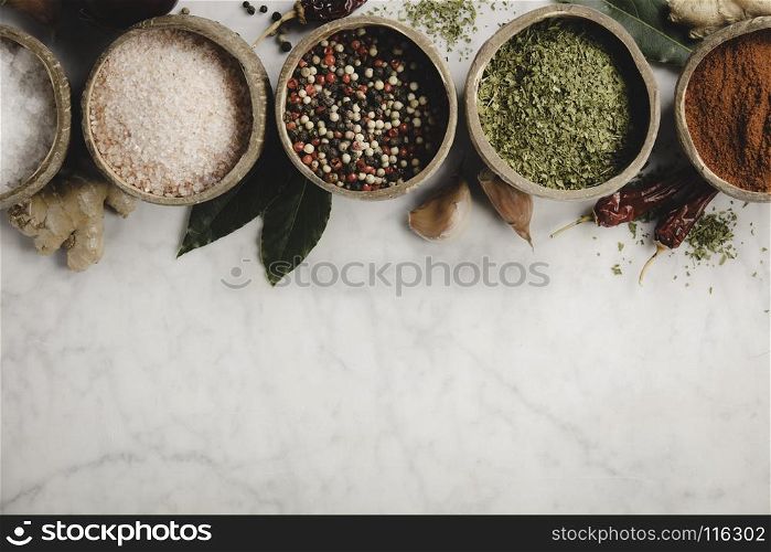 Set of spices on rustic murble background. Coconut shell bowls with paprika salt parsley and pepper. Cooking concept