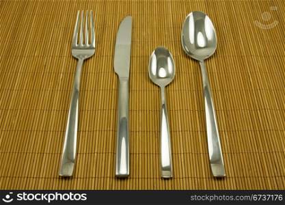 set of stainless steel tableware on bamboo tablecloth
