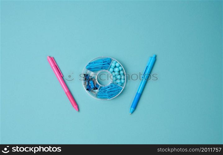 set of stationery objects: pen, paper clip, buttons and clip on a blue background. View from above